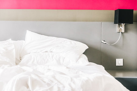 White pillow on messy and sheet bed decoration in bedroom interiorの写真素材