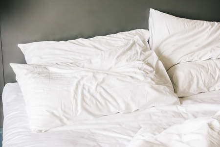 White pillow on messy and sheet bed decoration in bedroom interior