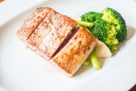 Selective focus point on tuna steak with vegetable in white plateの写真素材