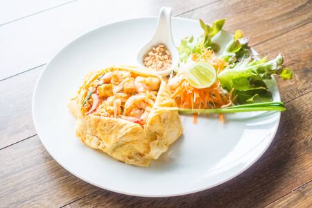Pad thai noodles in white plate on wooden backgroundの写真素材