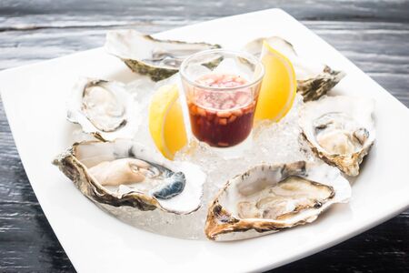 Raw fresh oyster shellfish with sweet sauce in white plate - seafood styleの写真素材