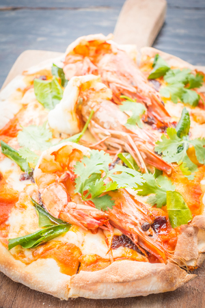 Spicy and Seafood Tom Yum Kung pizza with shrimp on top in wooden plateの写真素材