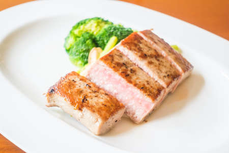Selective focus point on tuna steak with vegetable in white plateの写真素材