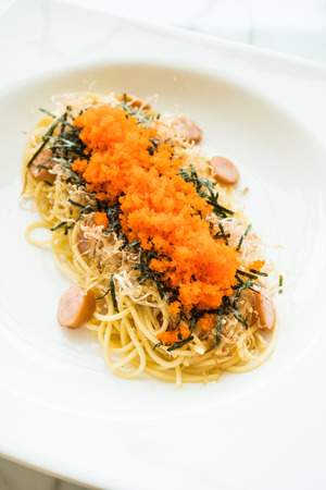 Spaghetti with sausage , shrimp egg , seaweed , and dry squid on top in white plate - Italian food styleの写真素材
