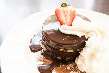 Chocolate pancake with strawberry on top in white plate