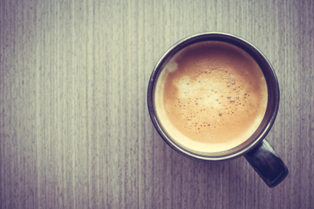 Latte coffee in black cup on wooden tableの写真素材