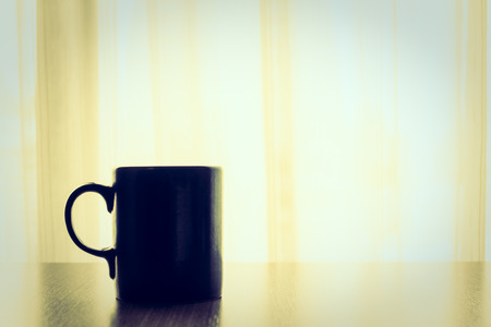 Latte coffee in black cup on wooden table - Vintage Filter and Sunflare filterの写真素材