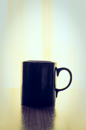 Latte coffee in black cup on wooden table - Vintage Filter and Sunflare filterの写真素材