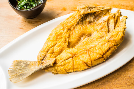 Fried sea bass fish in white plate with spicy and sweet sauce in Thai style - Processing Warm white balanceの写真素材