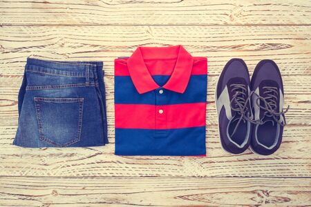 Beautiful casual men fashion set with Polo shirt short jeans pants and shoes on wooden background - Vintage light Filterの写真素材