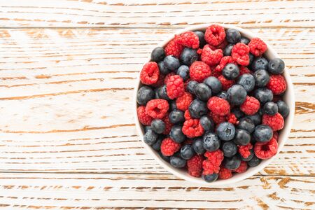 Group of Blueberry and Rasberry fruit in bowl on wooden background