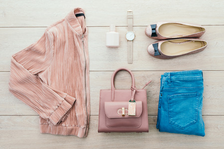 Beautiful casual woman fashion set with Pink Jacket Jeans Pants Handbag and Shoes on wood background - Vintage light Processingの写真素材