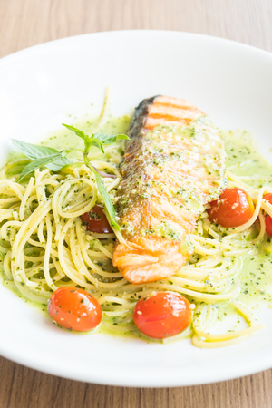 Spaghetti pesto salmon in white plate on wooden tableの写真素材