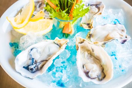 Raw and fresh Oysters in white plate with vegetable