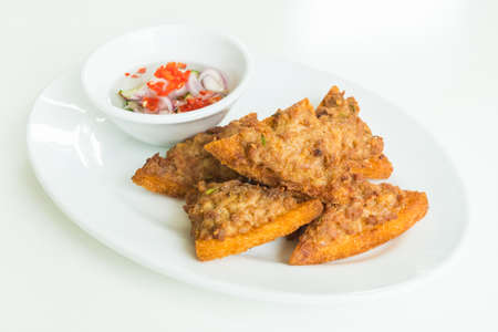 Fried bread with minced pork spread in white plate with sauce
