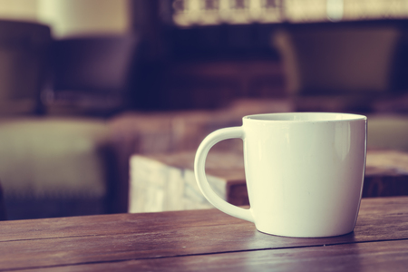 White cofffee cup on wooden table in coffee shop cafe - Vintage Filterの写真素材