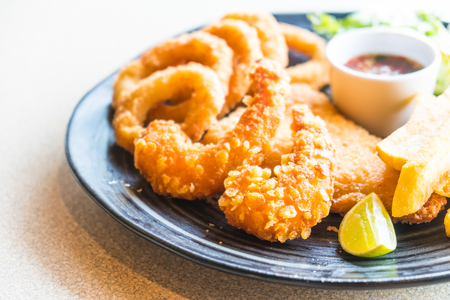 Fried Seafood platter with french fries in black plateの写真素材
