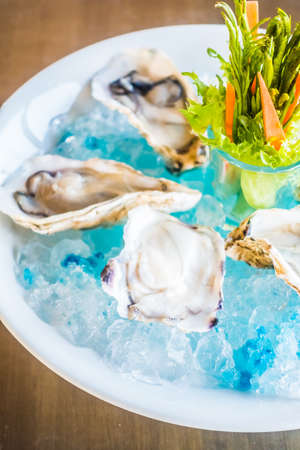 Raw and fresh Oysters in white plate with vegetableの写真素材