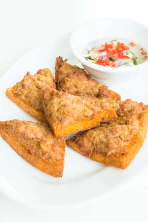 Fried bread with minced pork spread in white plate with sauceの写真素材