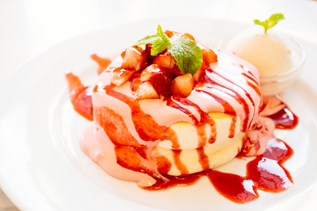 Sweet pancake dessert with strawberry fruit on top and sauce in white plate - Color Filter Processingの写真素材
