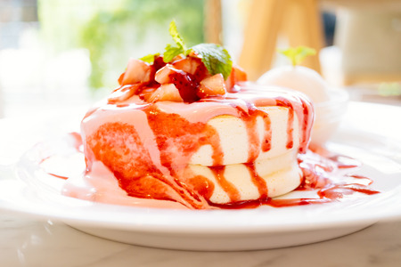 Sweet pancake dessert with strawberry fruit on top and sauce in white plate - Color Filter Processingの写真素材