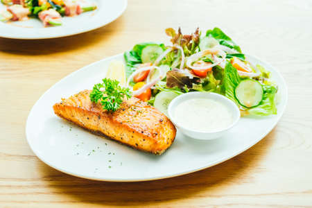 Salmon meat fillet steak with vegetable salad in white plateの写真素材