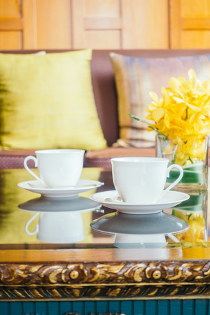 Vase flower and white coffee cup on table and pillow on sofa decoration of living room interiorの写真素材