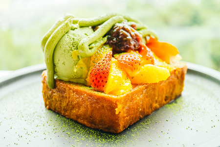 Sweet dessert bread toast with matcha ice cream and strawberry , orange in plate - Color filter Processingの写真素材