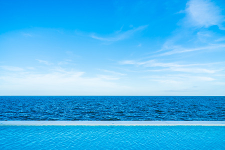Infinity swimming pool with sea and ocean view on blue sky backgroundの写真素材