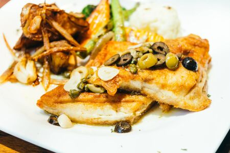 Grilled sea bass fish meat steak with vegetable in white plateの写真素材