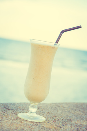 Ice drinking banana smoothies glass with sea and ocean background - Vintage Filterの写真素材