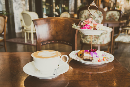 White cup with latte coffee and cake on table in cafeの写真素材