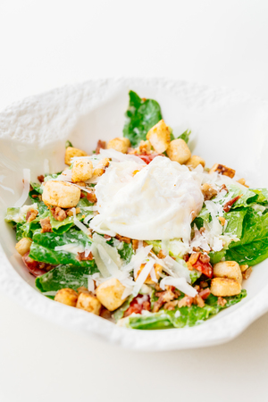 Caesar salad with fresh vegetable and egg in white bowl - Healthy food styleの写真素材