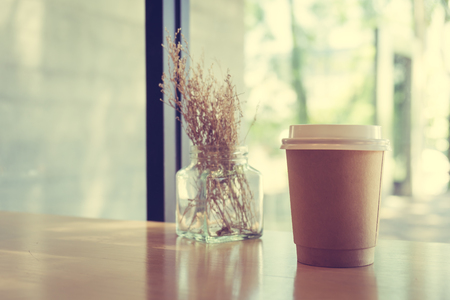 Hot latte coffee in paper cup on table in cafe - Vintage Filterの写真素材