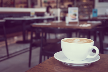 Hot latte coffee in white cup on table in restaurant and cafe - Vintage Filterの写真素材
