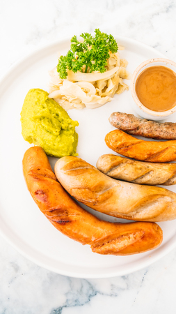 Mixed grill sausage barbecue in white plate with sauceの写真素材