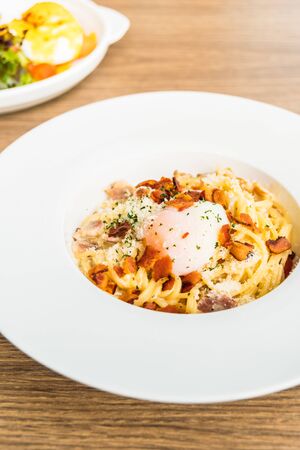 Spaghetti carbonara with egg on top in white plate - Italian food styleの写真素材