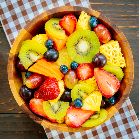 Mixed and assorted fruits with kiwi strawberry grape and other in bowl on wood table - Filter...