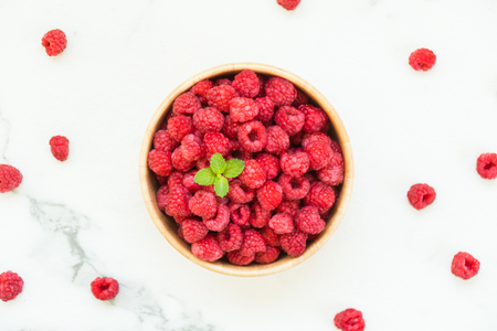 Red rasberries fruit in wood bowl on tableの写真素材