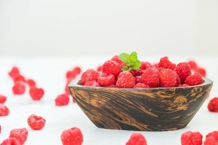 Red raspberries fruit in wood bowl on table