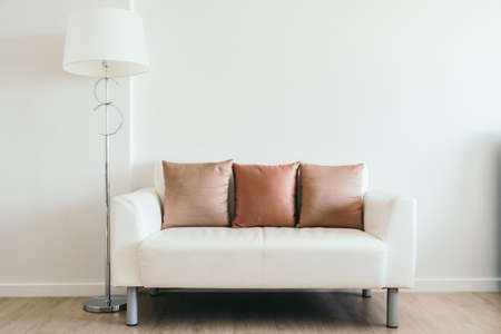 Comfortable pillow on white sofa with light lamp decoration in living room interiorの写真素材