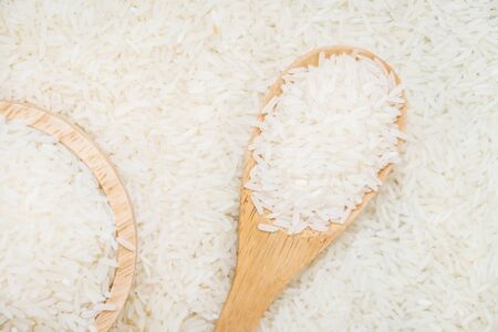 Raw Jasmine rice in wooden bowl  and spoon with grain and seedの写真素材