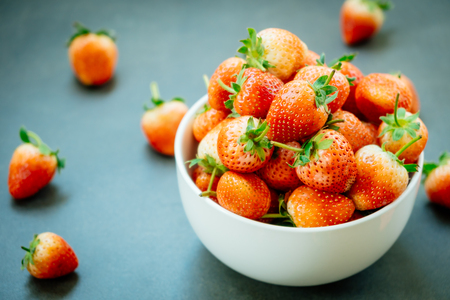 Strawberry fruit in white bowl on black stone backgroundの写真素材