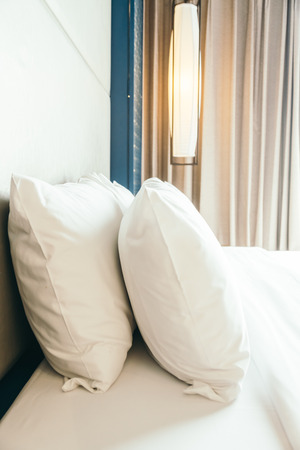 White comfortable pillow on bed decoration in hotel bedroom interiorの写真素材
