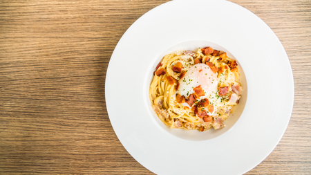 Spaghetti carbonara with egg on top in white plate - Italian food styleの写真素材
