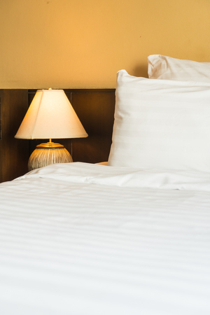 White comfortable pillow on bed with light lamp decoration interior of bedroomの写真素材