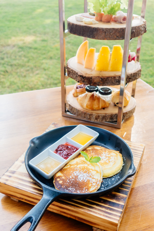 Pancakes with sweet sauce in black pan for breakfastの写真素材