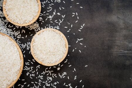 Raw Jasmine rice in wooden bowl  and spoon with grain and seedの写真素材