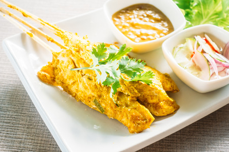 Grilled chicken satay in white plate with sauceの写真素材