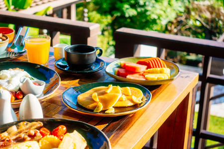 Healthy breakfast set with egg bacon pancakes orange juice milk bread coffee and other on wooden tableの写真素材